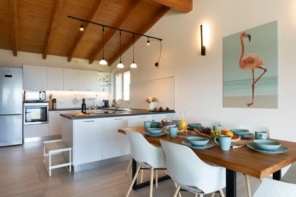 Bright modern kitchen and dining area with wooden ceiling and set breakfast table