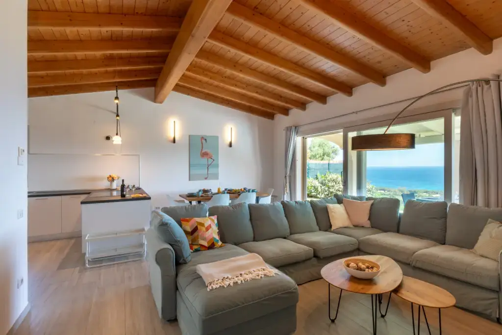 Spacious living room with sea view, large sofa, and open-plan kitchen with wooden ceiling